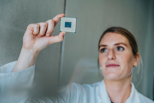 Scientist holding computer chip while standing against wall at clinic