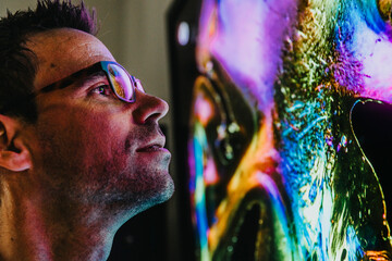 Scientist wearing eyeglasses examining projection of human brain with nerve fiber while standing at laboratory
