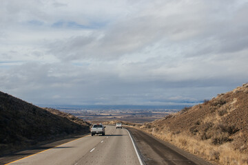 A beautiful landscape with a highway along which cars and trucks drive, on a sunny autumn day among the mountains, a blue sky with fluffy gray-blue clouds. Oregon, USA, 12-5-2019