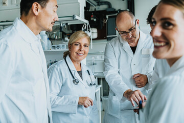 Smiling scientist working together with digital tablet while standing at laboratory
