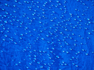 Naklejka na ściany i meble Water drops on waterproof membrane fabric. Detail view of texture of blue synthetic waterproof cloth. Morning dew on tent.