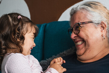 Granddaughter and grandmother look at each other knowingly while laughing.