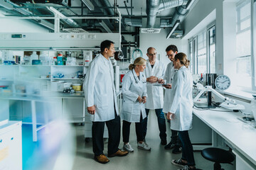 Male and female scientist with digital tablet working together while standing at laboratory
