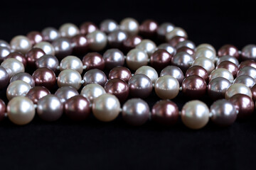 Necklace of pearls of different colors on black velvet.