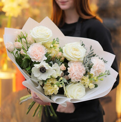 Flower shop. Beautiful bouquet of mixed flowers in light bright color in woman's hands. Work of the florist at a flower shop.  Fresh cut flower.