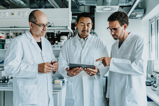 Team of scientist using digital tablet while standing at laboratory