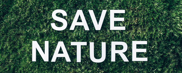 Inscription Save Nature on moss, green grass background. Top view. Copy space. Banner. Biophilia concept. Nature backdrop