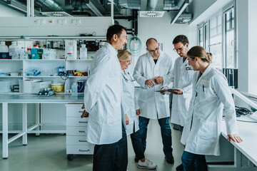 Team of scientist with digital tablet working together while standing at laboratory