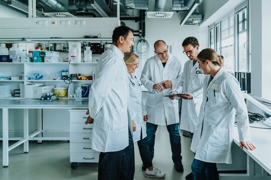 Team of scientist with digital tablet working together while standing at laboratory