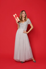 Happy woman with gift box on red background. Christmas party