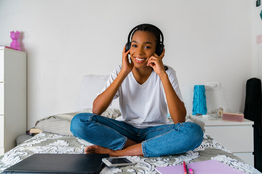 Young Girl With Cross Legged Listening To Music While Sitting At Home