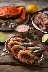 Macro shot view of plates with assorted seafood served with spices on rustic wooden background. Cooked crab, shrimps and baby octopuses for dinner. Seafood concept.