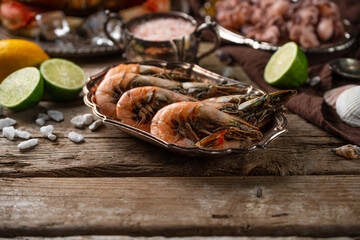 Close-up view of plates with assorted seafood served with spices on rustic wooden background. Cooked crab, shrimps and baby octopuses for dinner. Seafood concept.