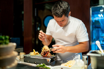 Chef garnishing food while standing in commercial kitchen