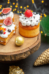 front view delicious cream cakes around new year tree toys on dark floor cake sweet photo cream dessert
