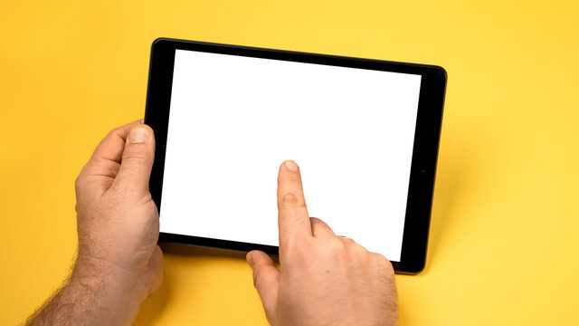 Cropped close up view mock up image man hand hold black tablet pc white blank screen isolated yellow bright background. Digital modern gadget, remote distance work concept. Free empty space for text