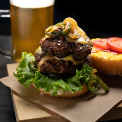 Cheese burger with caramelized onion and jalapeno pepper on dark background