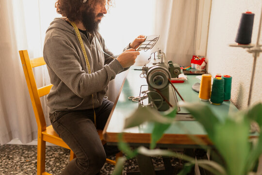 Mature man making protective face mask sitting at home