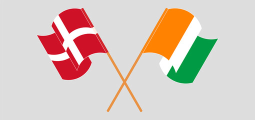 Crossed and waving flags of Denmark and Republic of Ivory Coast