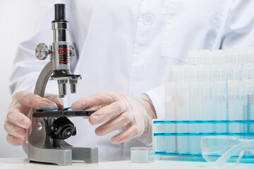 Macro shot view of laboratory assistant in protective gloves analyzes with microscope covid-19 vaccine on white background. Backstage of scientific discovery. Healthcare and medicine concept.