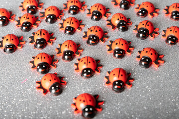 large group of wooden lady bugs on a silver glitter background