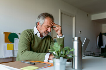 Mature man worried while working on laptop at home