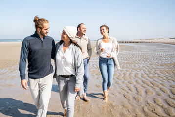 Mother and son in law talking while walking with daughter and father in background at beach