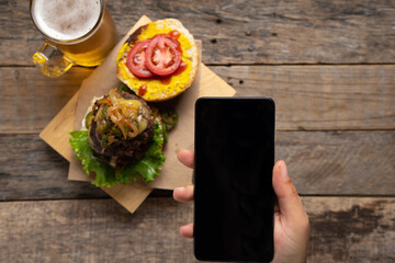 Cell phone looking cheese burger with caramelized onion and jalapeno pepper on wooden background