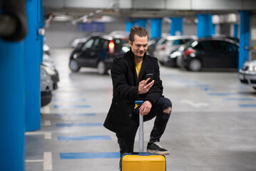 Man in underground car parking garage. Man with a rolling suitcase