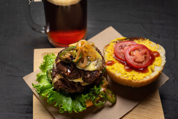 Cheese burger with caramelized onion and jalapeno pepper on dark background