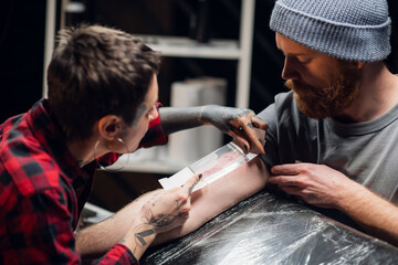 Girl tattoo artist takes care of the young man's hand after tattooing. Makes the dressing...