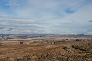Beautiful autumn landscape with mountains, dry grass, trees and fields, unusual great sky with dark gray clouds