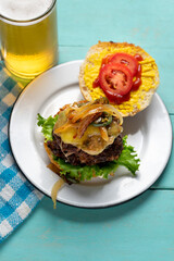 Cheese burger with caramelized onion and jalapeno pepper on turquoise  background