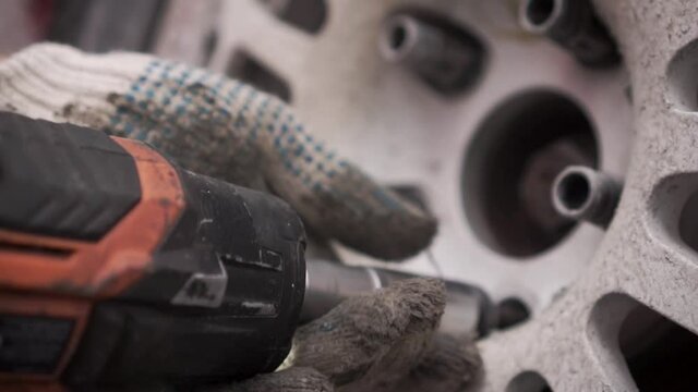Close-up of replacing a wheel with an electric wrench. Footage. Live footage from the pit stop of the racing rally site.