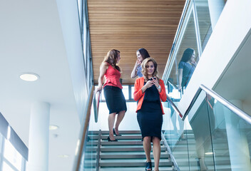 Female coworkers moving down steps in office