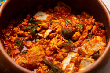 Mexican scrambled eggs in red sauce with poblano pepper and cheese on white background