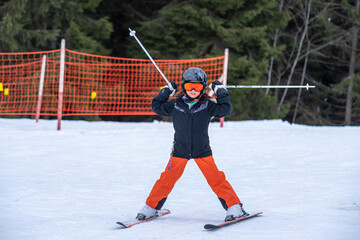 skiing in the snow. One Asian girl holding ski sticks in hands. Vacation in Switzerland. Happy childhood.