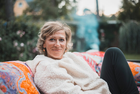 Smiling woman relaxing while sitting on sofa at back yard