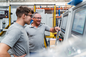 Male engineers brainstorming while testing machine at factory