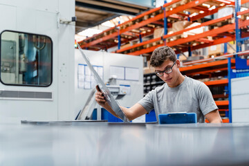 Young male engineer examining product at factory