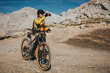 Female cyclist photographing at Picos de Europa National Park on sunny day, Cantabria, Spain