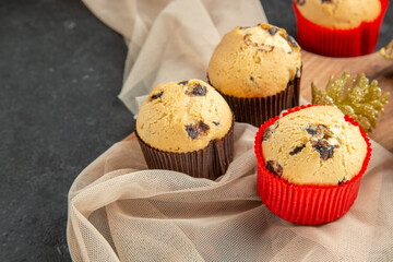 Front close view of tea break with delicious small cupcakes and accessory on towel on black background