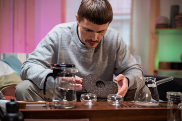 A man in an intimate home environment prepares for a Chinese tea ceremony, inhales the aroma of fresh raw black tea