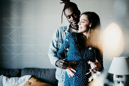 Multi ethnic couple with star shaped lights spending leisure time together at home