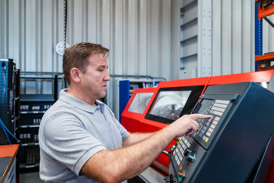Industrial male manual worker operating control panel at industry