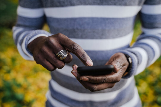 Man holding smart phone in park during autumn