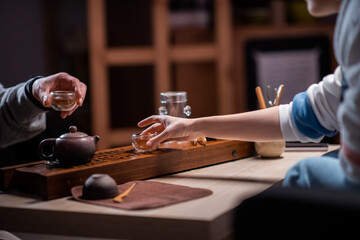A man and a woman drink fragrant tea from glass bowls during a tea ceremony. Blurry background. Without a face
