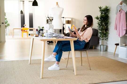 Female tailor examining fabric swatches while sitting on chair in studio