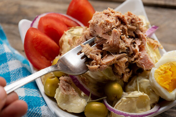 Tuna salad with potatoes and boiled egg called nicoise on wooden background