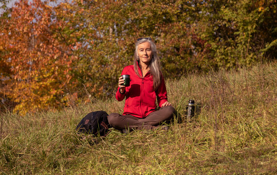 Woman holding thermos cup while sitting on mountain at Alpine Foothills, Germany
